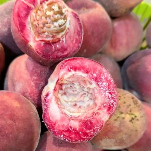 pêche de vigne sanguine coupée en deux, le noyau se détache d'une chair violette flashi